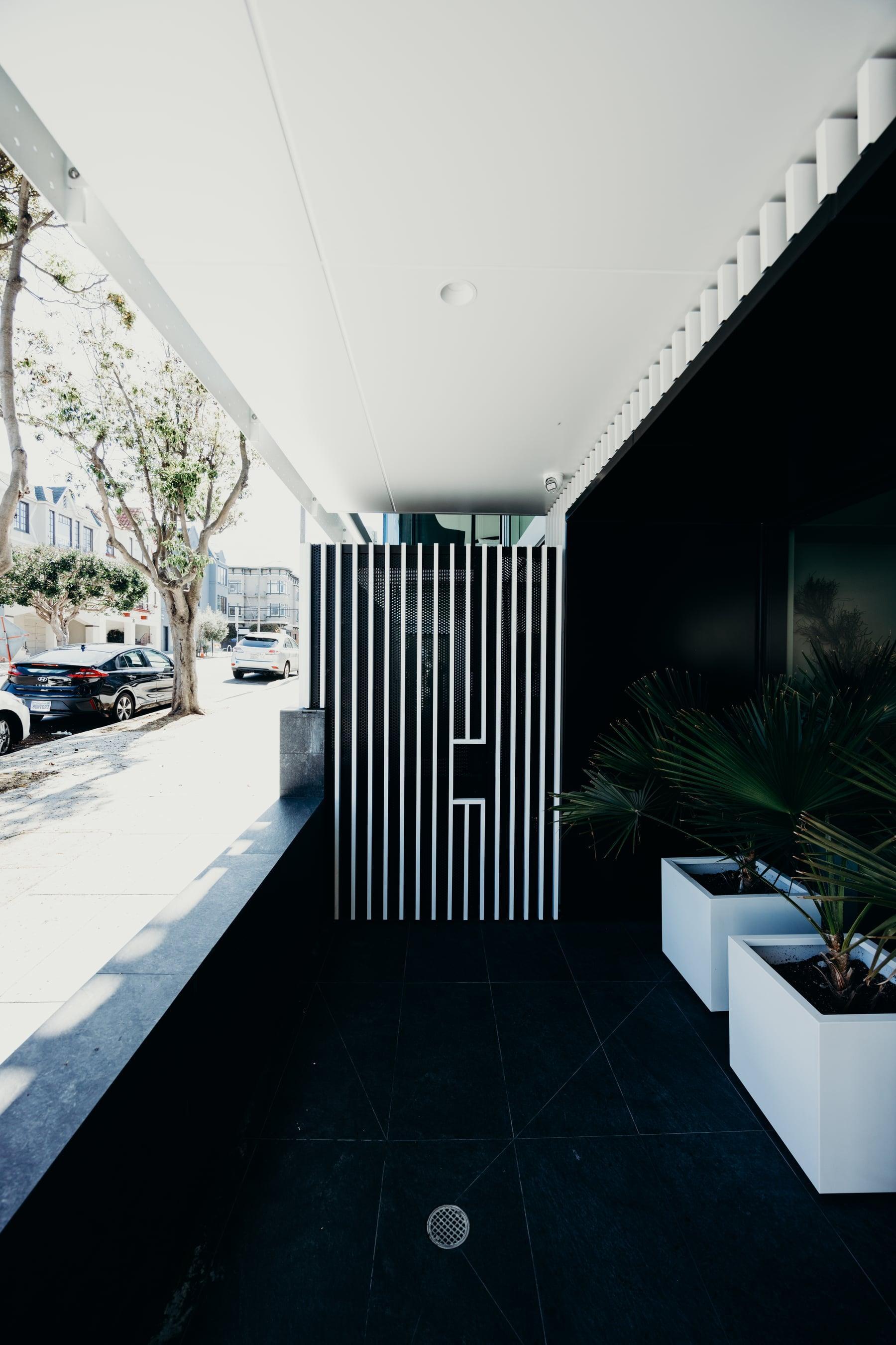 Narrow entry walkway with white vertical fins and planters