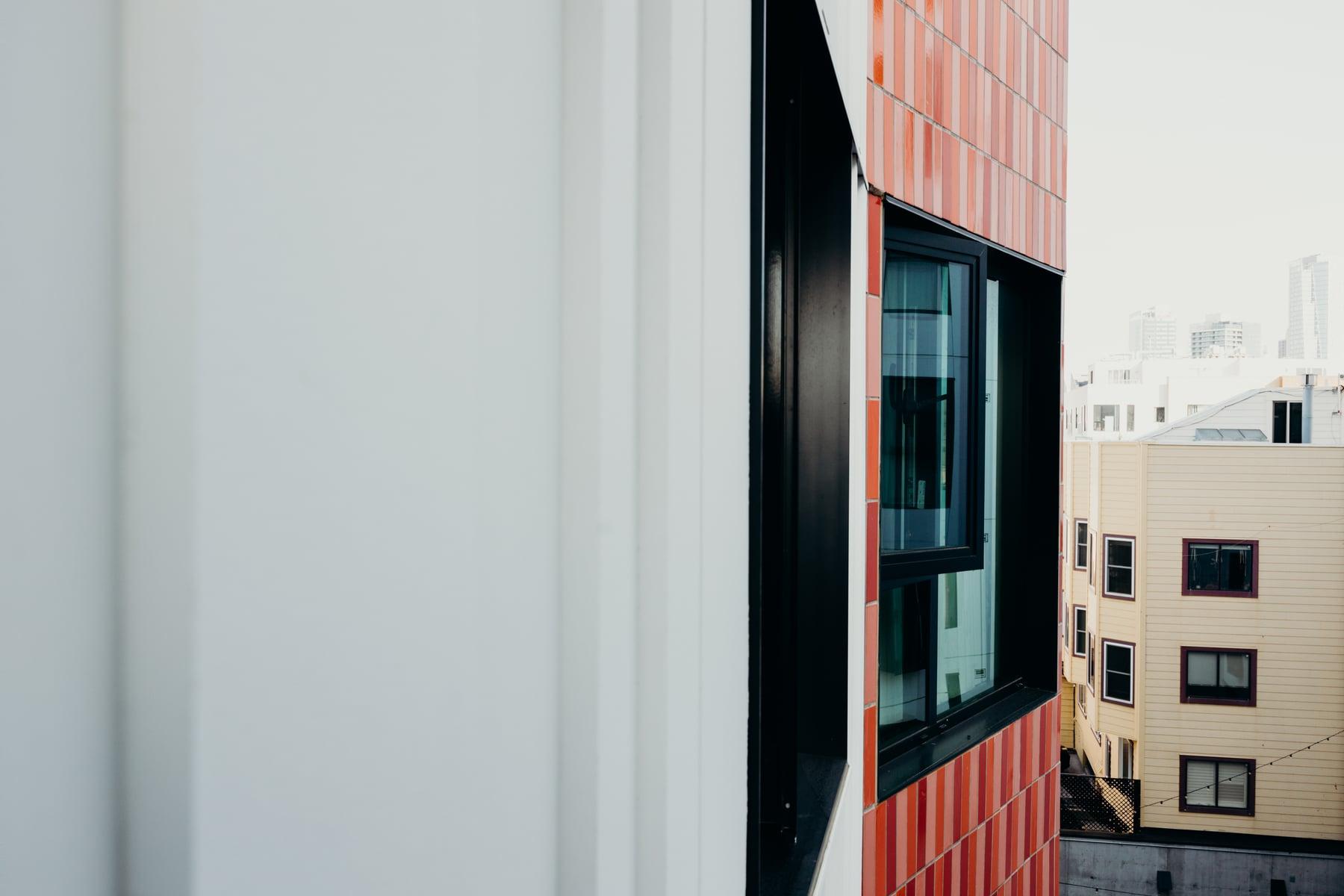 Orange tile cladding around a dark-framed window beside a white wall