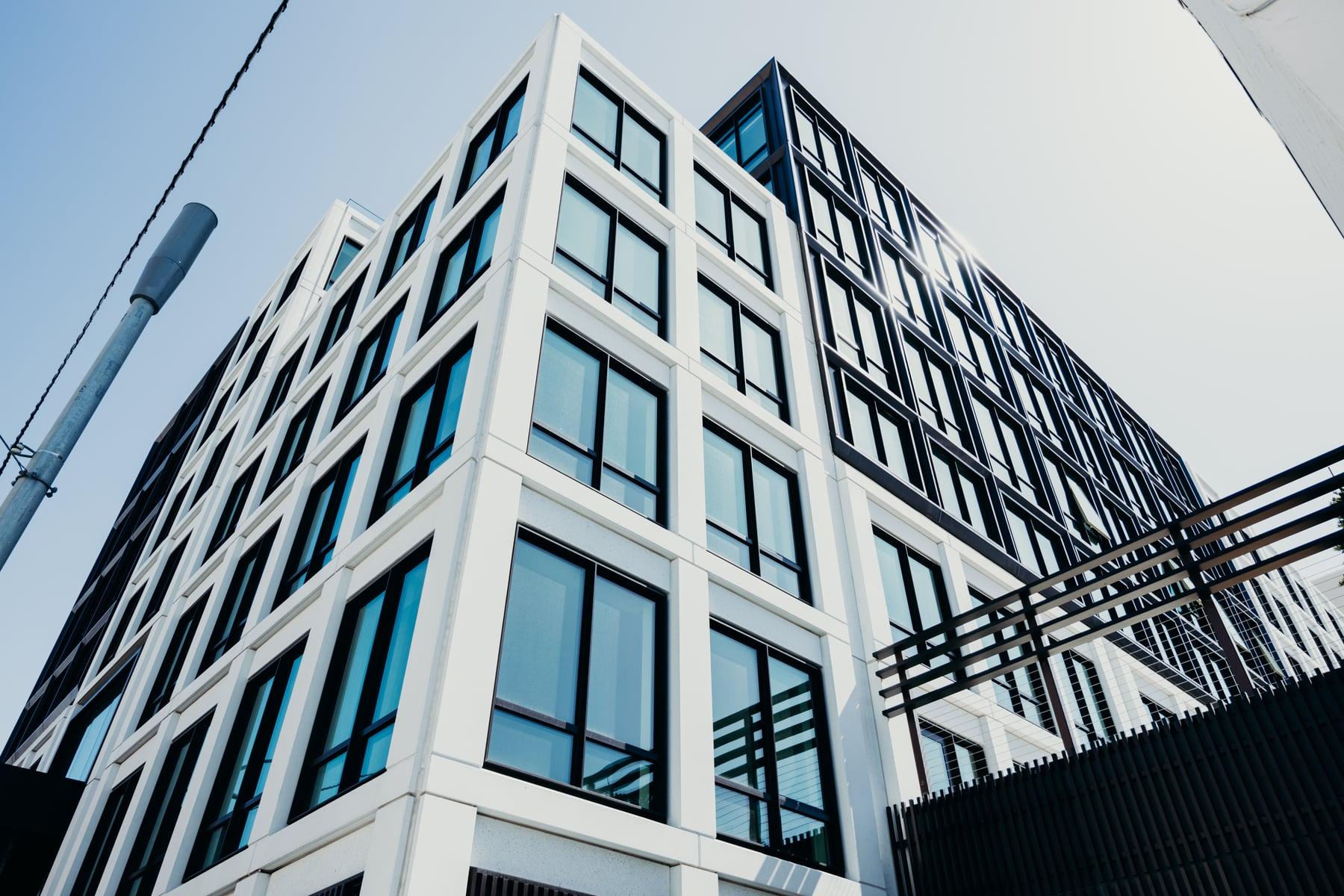 Looking up the white facade of 2465 Van Ness, with deep-set dark-framed windows at the corner