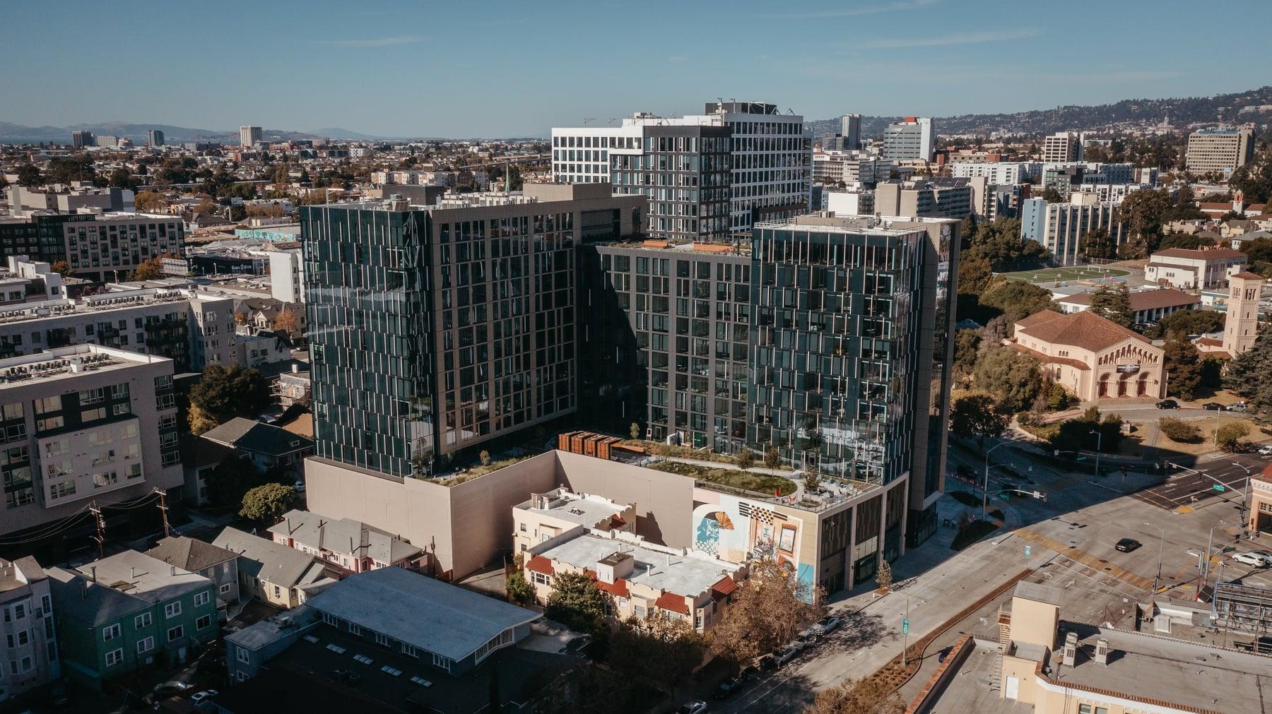 Aerial view of two glass-clad towers in Oakland among lower surrounding buildings