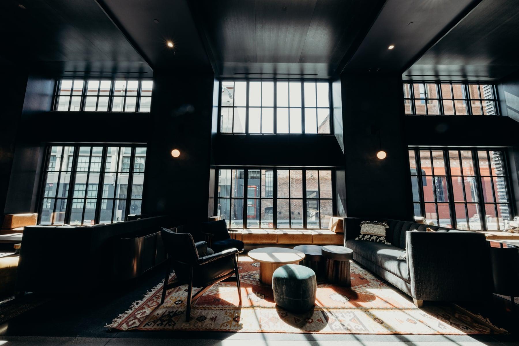 Double-height lounge with black-framed multi-pane windows, sofas and a patterned rug