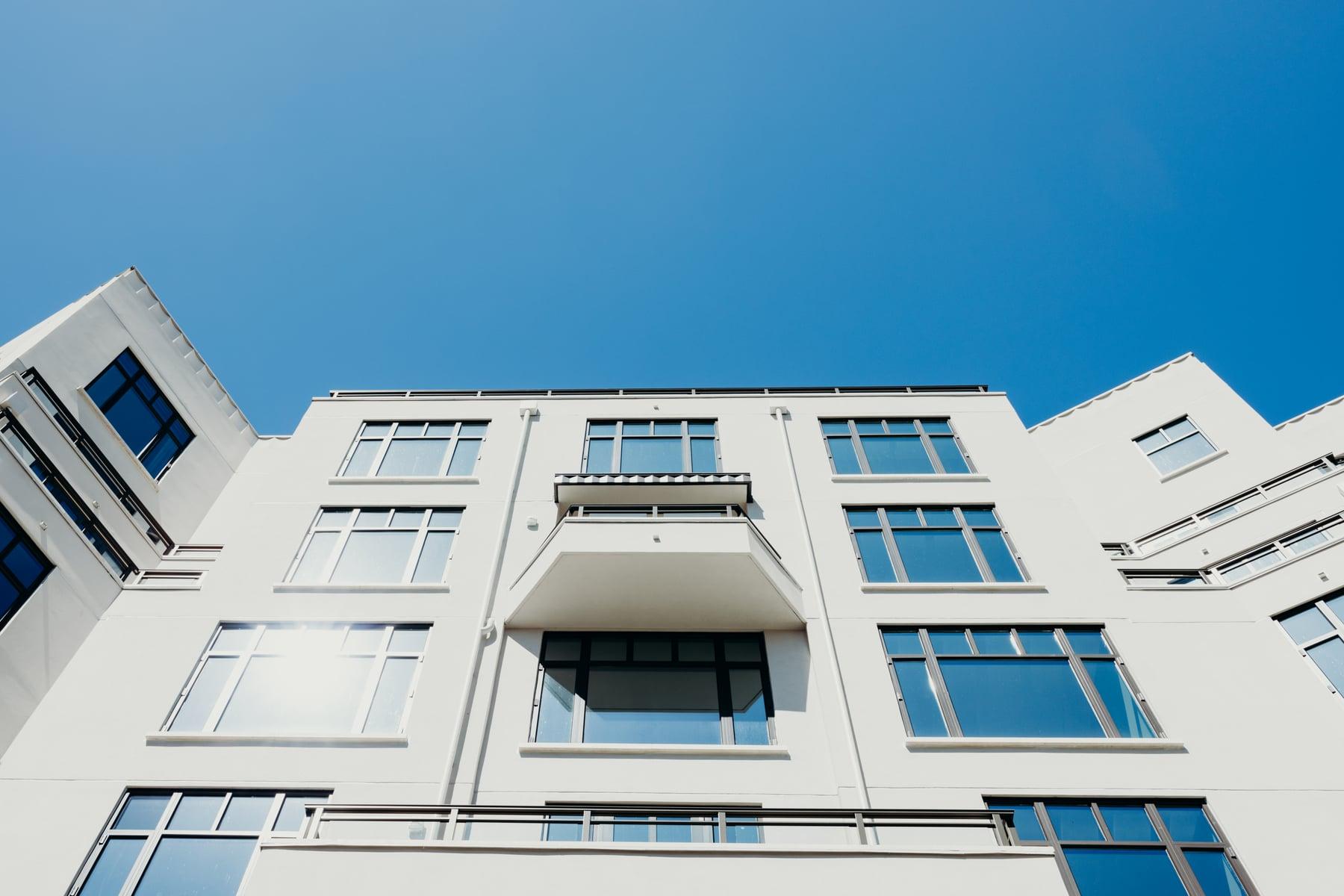 Upper floors of the building with dark-framed windows and a small balcony against blue sky