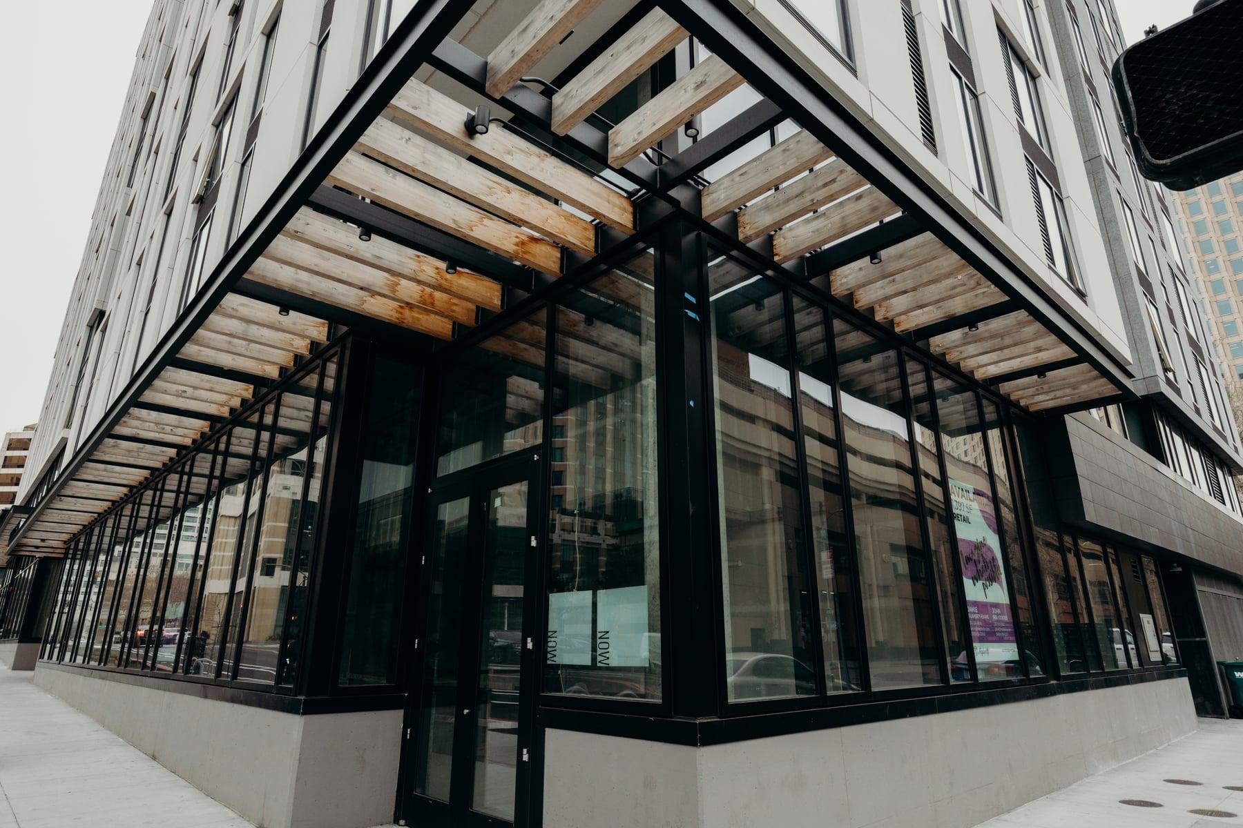 Corner storefront at 1100 Clay Street with black-framed glass under a wood-slat canopy
