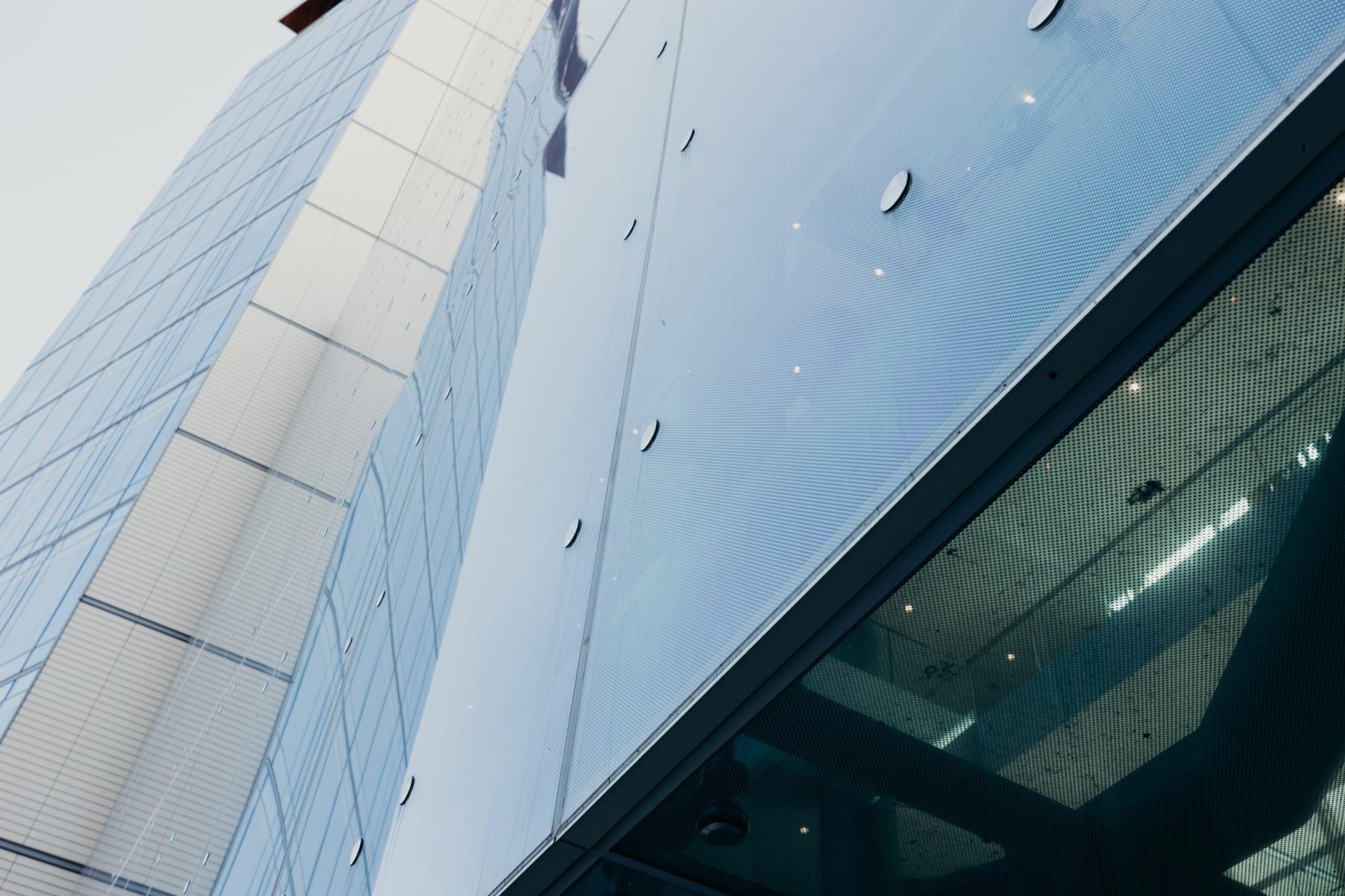Looking up the Gateway facade, with metal panels and large glass panels held by round point fittings