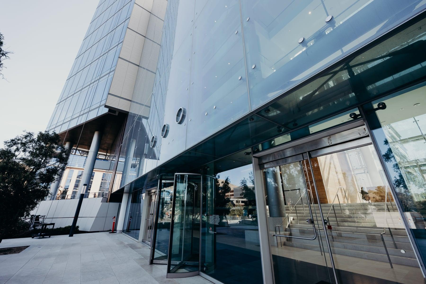 Gateway entrance under a point-fixed glass canopy, with revolving and swinging glass doors