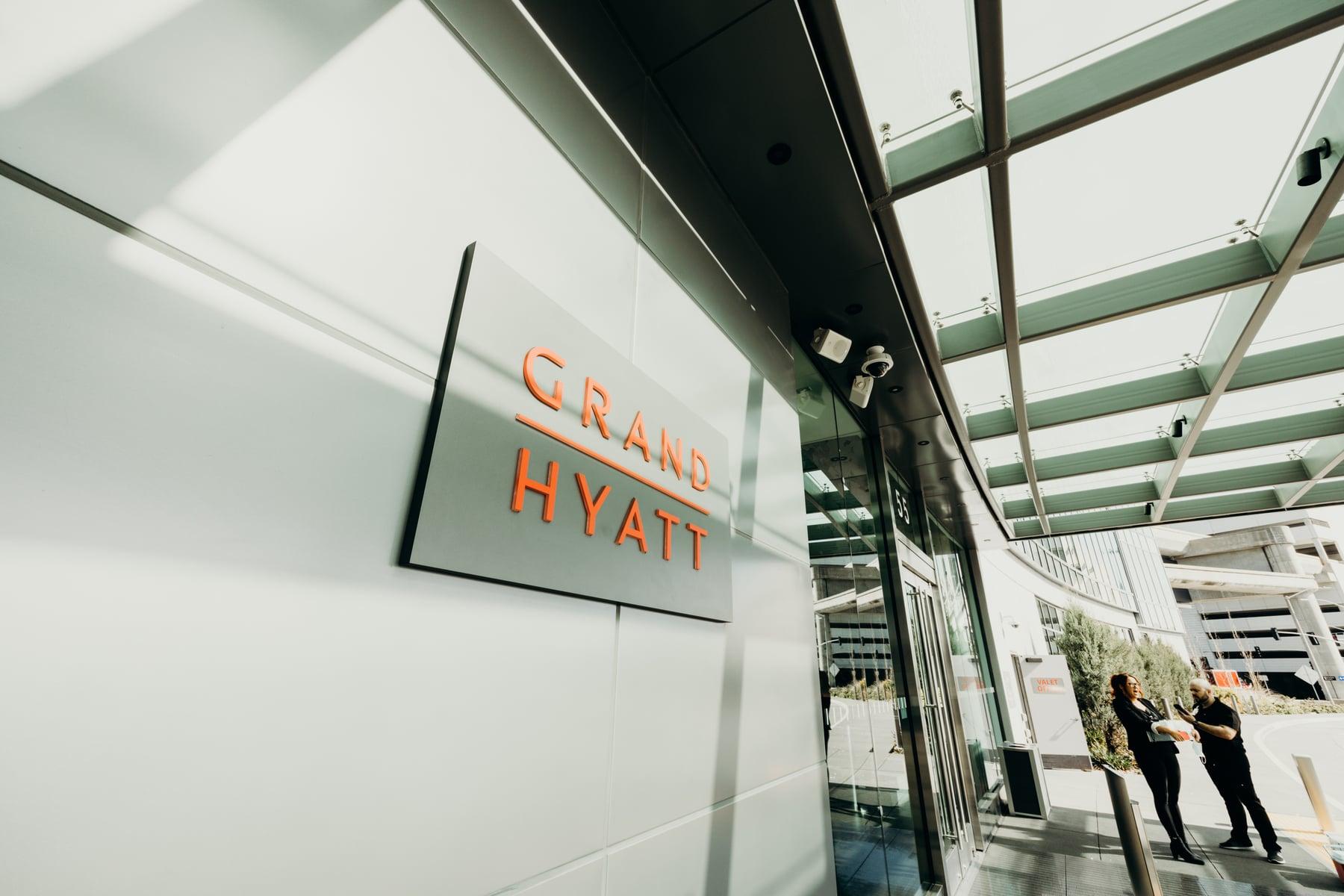 Grand Hyatt sign on a panel wall beside the glazed entrance doors under the canopy