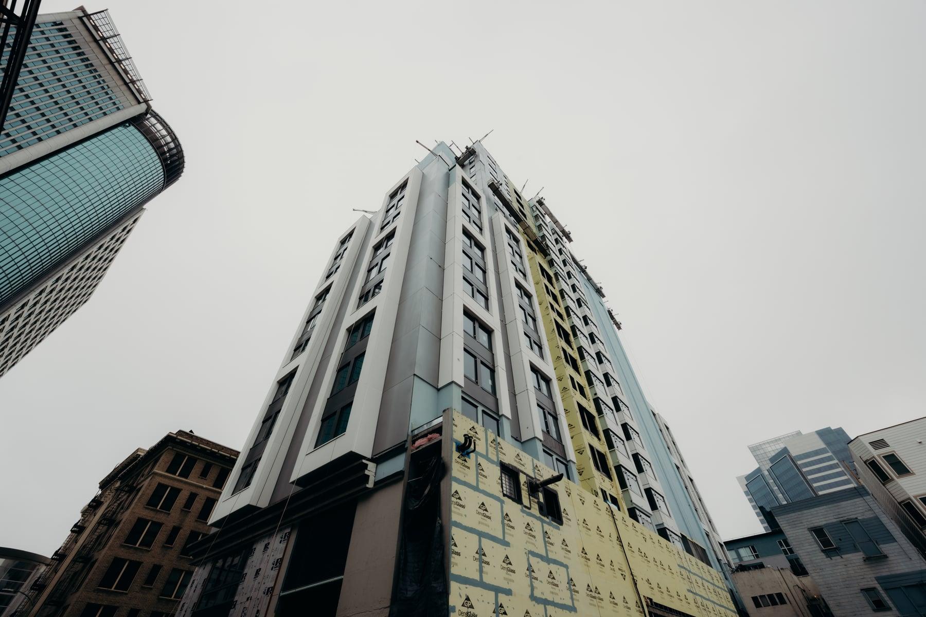 Looking up at the Oakland Marriott hotel tower during construction, with panels and windows installed and the lower floors not yet clad