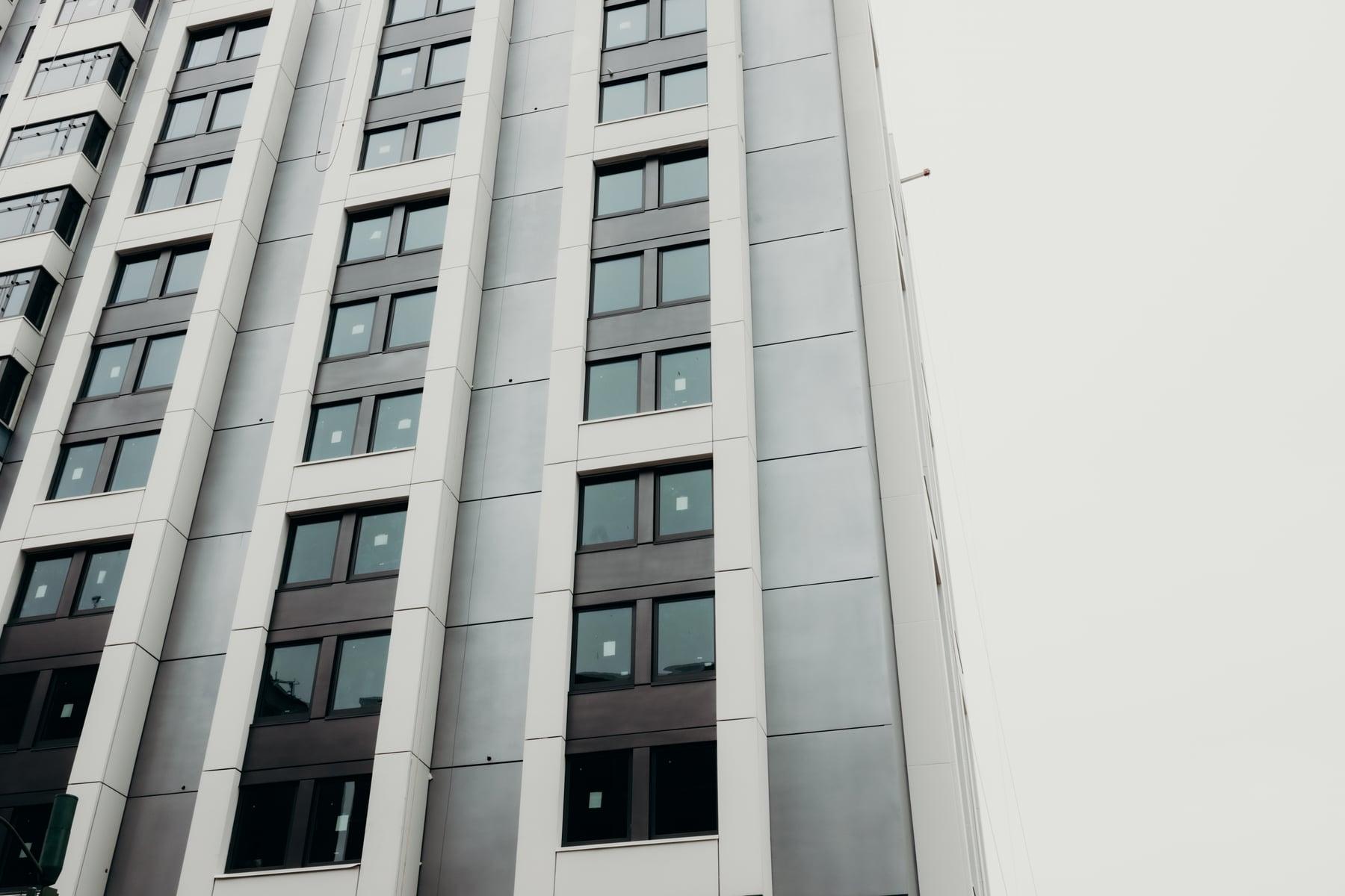 Close view of the hotel tower facade: tall light gray panels and dark-framed windows
