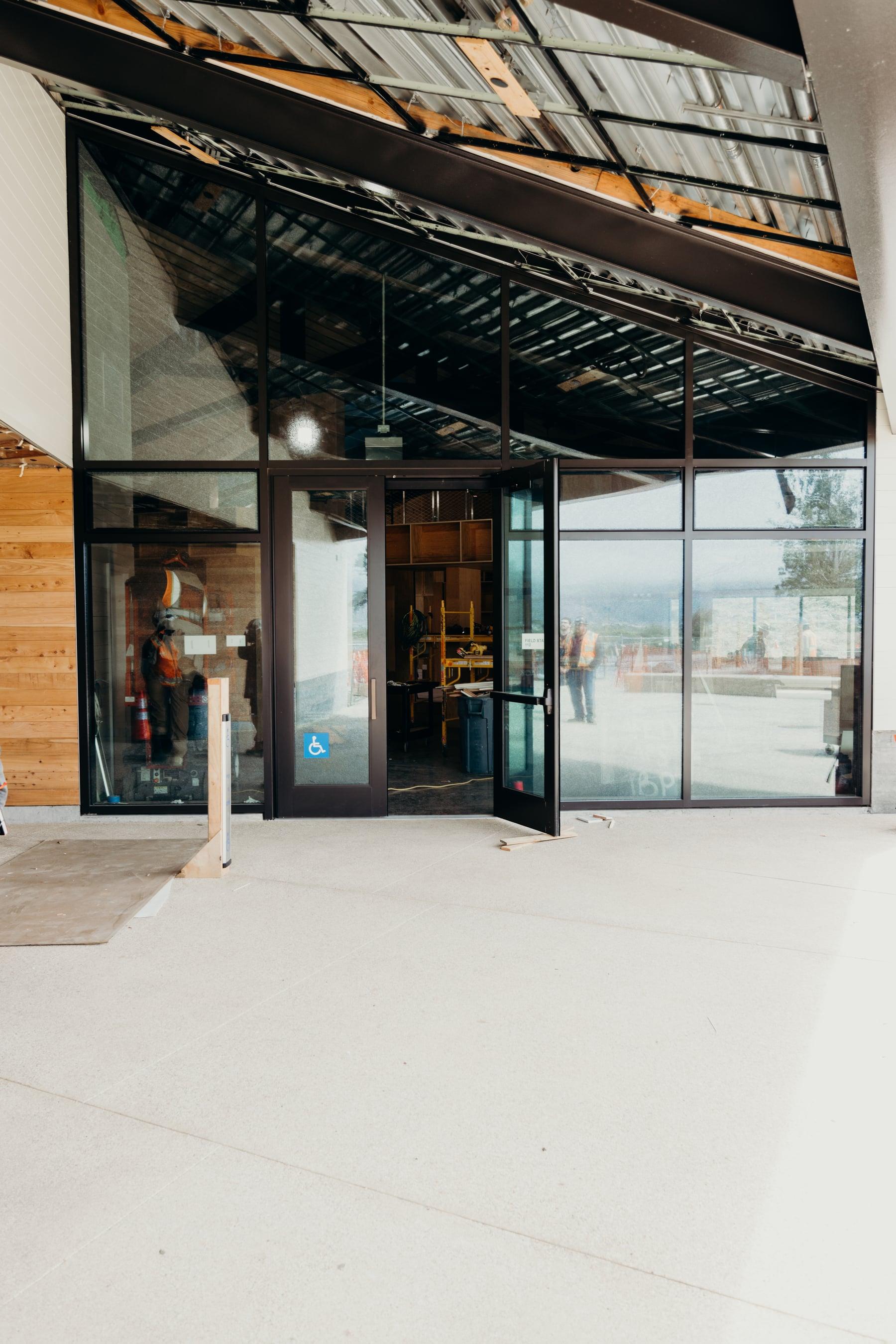 Black-framed glass entrance doors and sidelights beneath a louvered canopy