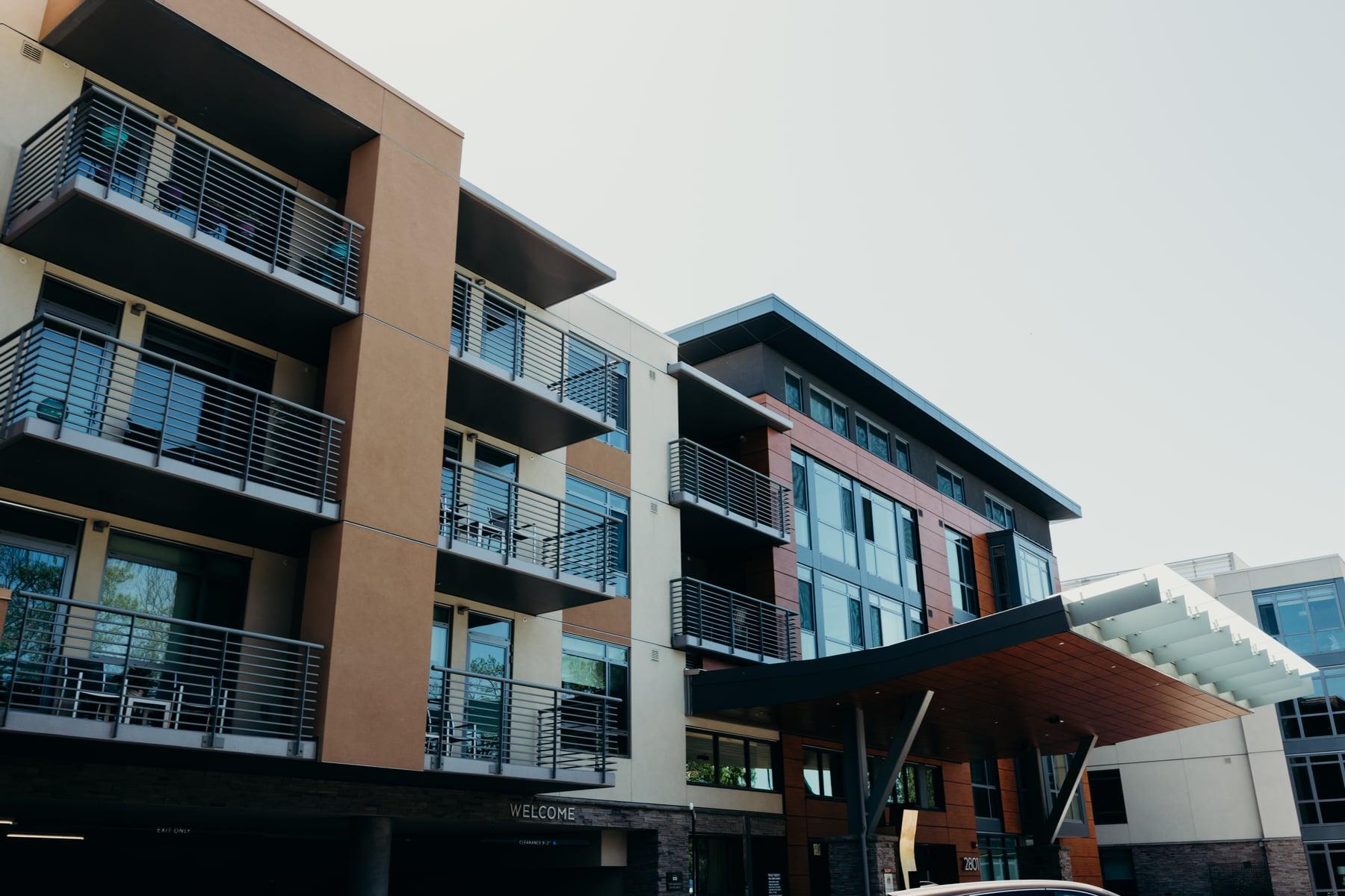 Balconies with metal railings on a multi-story building, with a sloped canopy over the entrance
