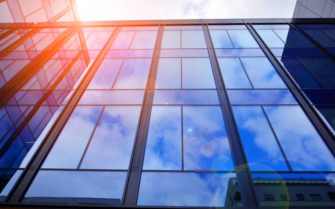 Modern high-rise building featuring large glazed windows that reflect the sky, showcasing sleek architectural design and natural light.